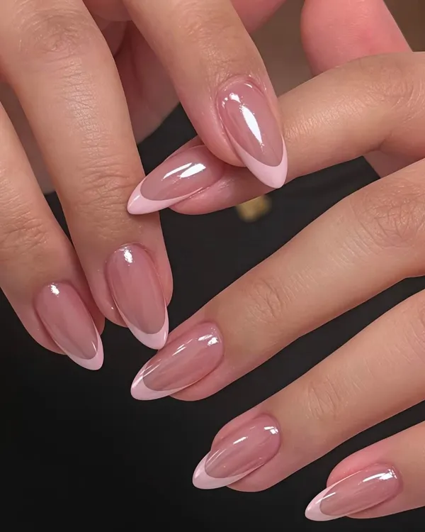 Uñas almendradas con francesa rosa y acabado brillante sobre fondo negro