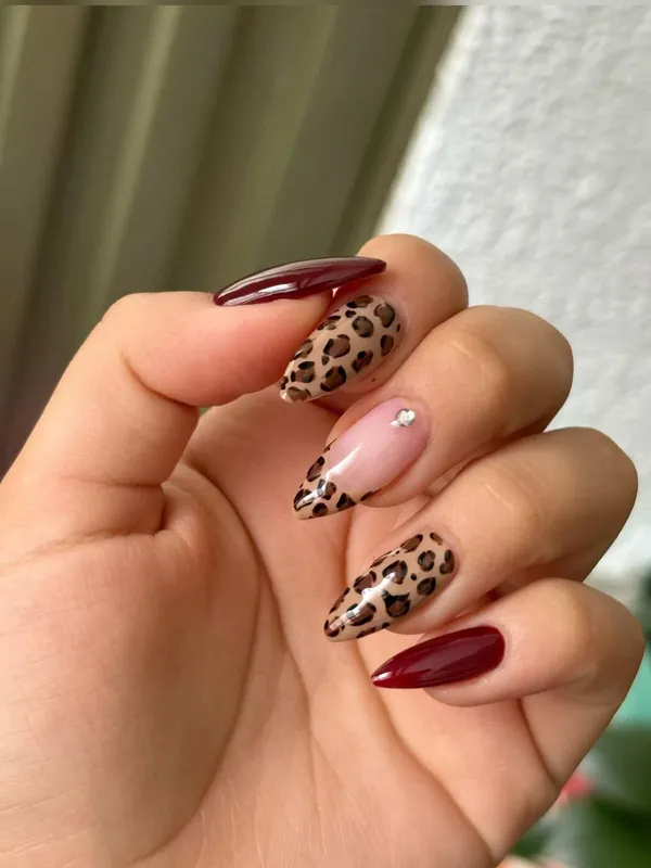 Uñas almendradas con print de leopardo combinadas con tono vino brillante