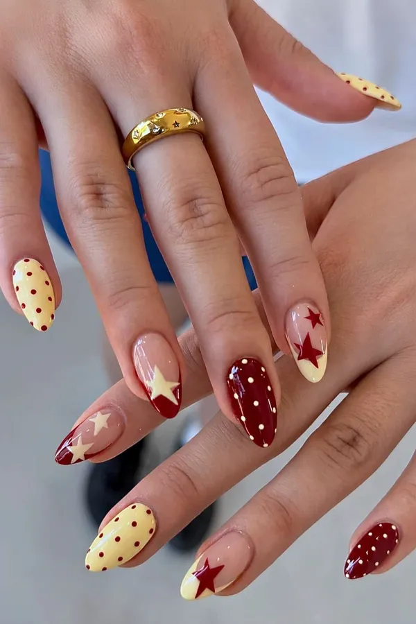 Uñas almendradas en rojo y crema con estrellas y lunares pintados a mano